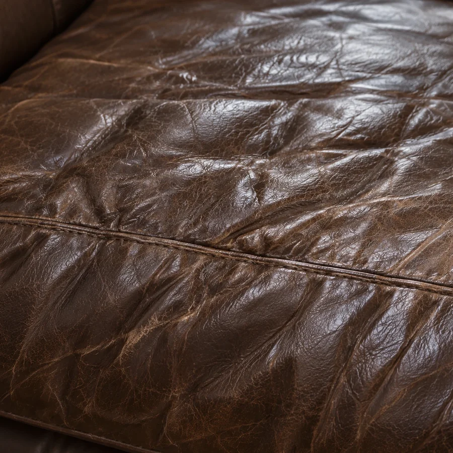 Heavy wrinkling running across the surface of a dark brown leather seat cushion